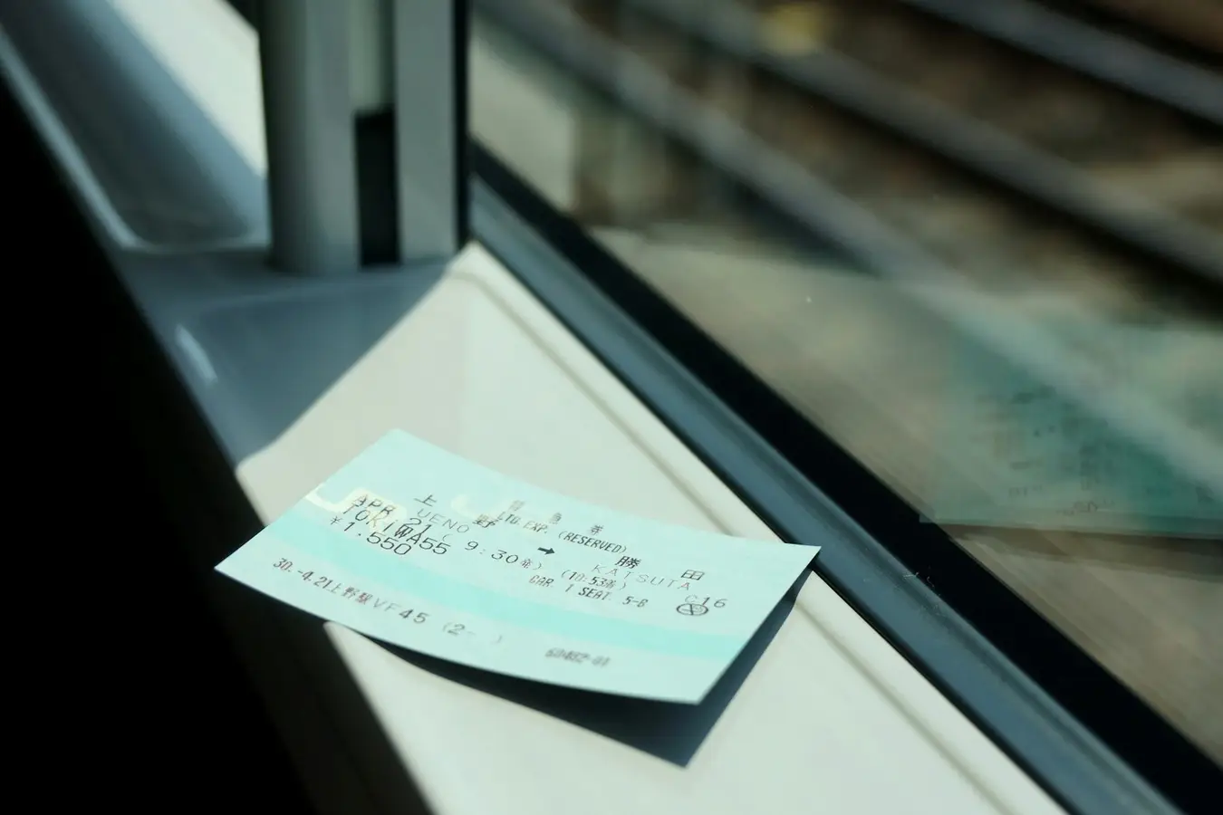Eine Fahrkarte liegt auf der Fensterbank eines fahrenden Zuges