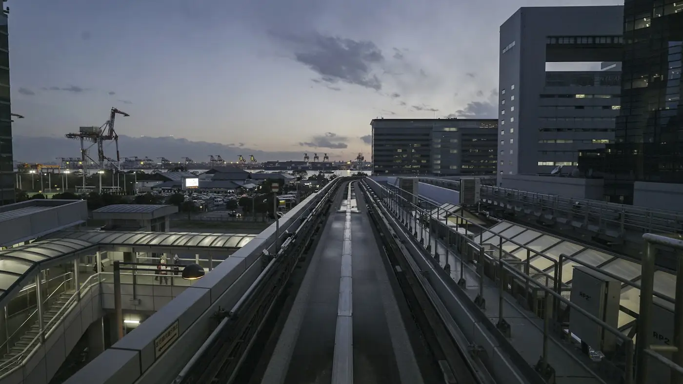 Gleisanlagen entlang eines Hafenbeckens, dahinter Kräne und Industriegebäude