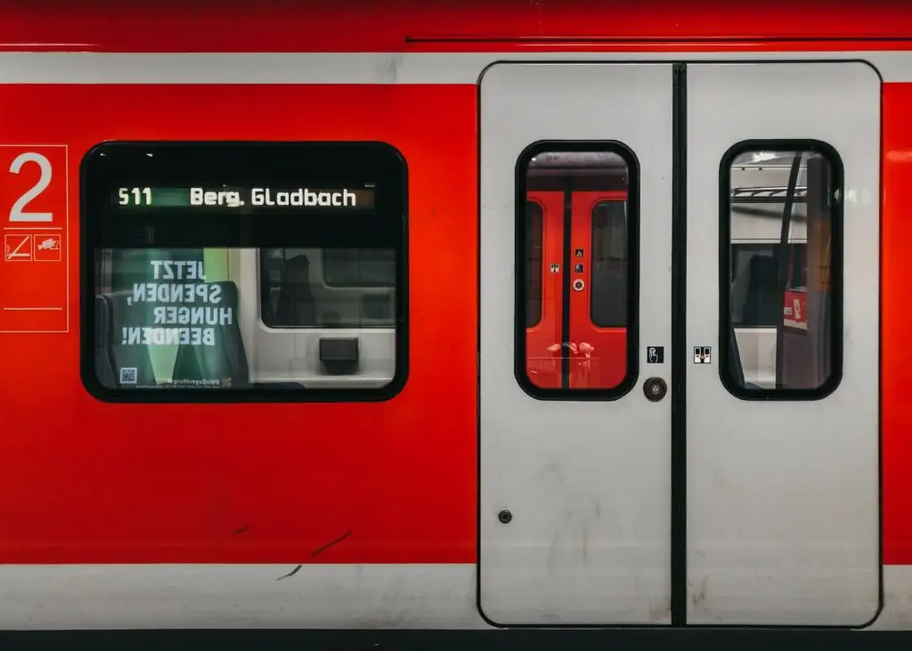 Nahaufnahme der Tür eines roten Nahverkehrstriebwagens mit Zielanzeige und Liniennummer