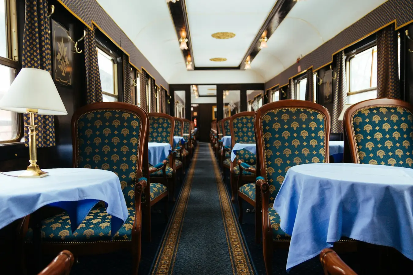 Blick durch einen historischen Speisewagen mit eingedeckten Tischen, Tischlampen und gepolsterten Sesseln