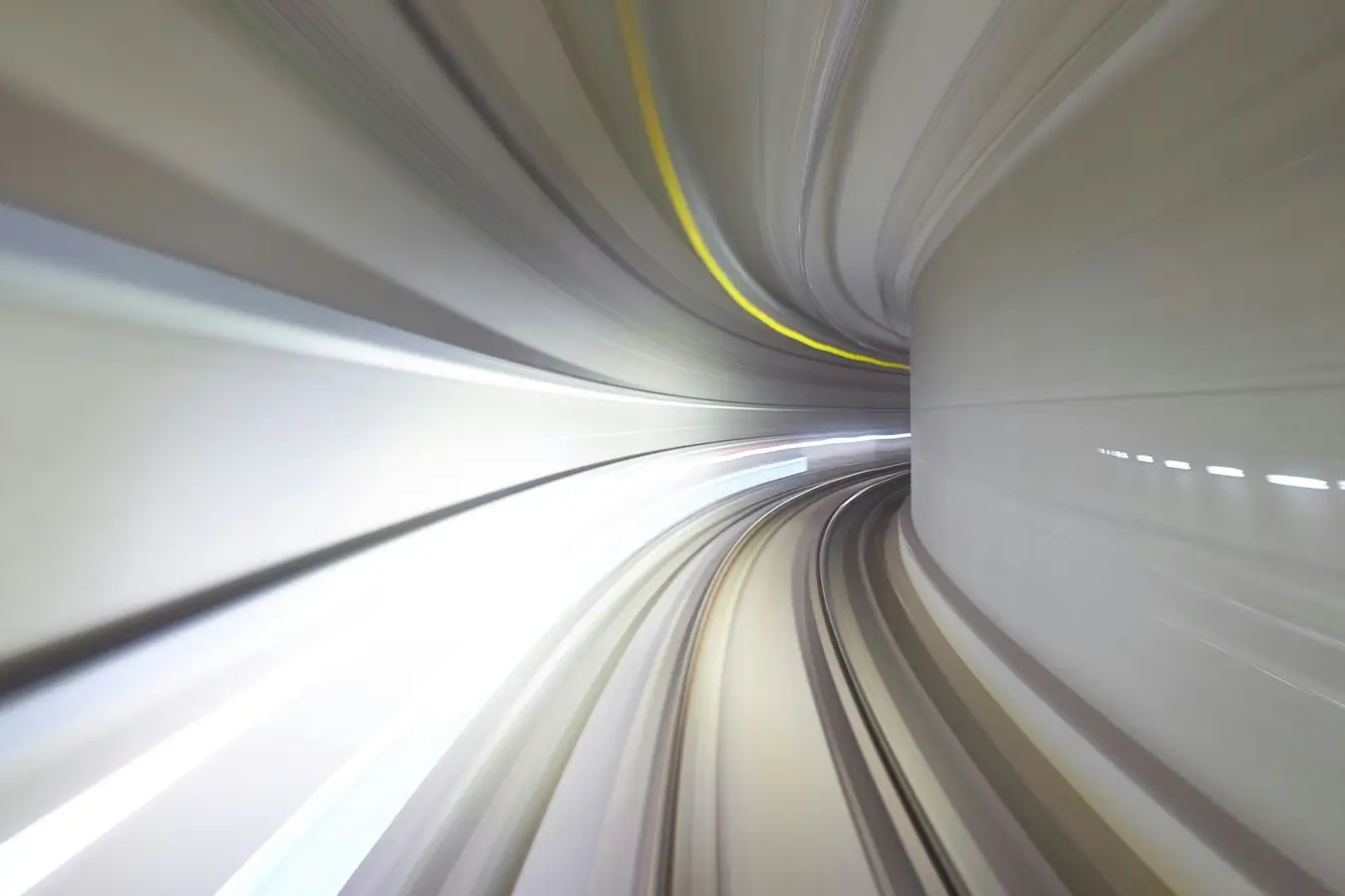 Blick in einen hell ausgeleuchteten Eisenbahntunnel mit geschwungener Röhre