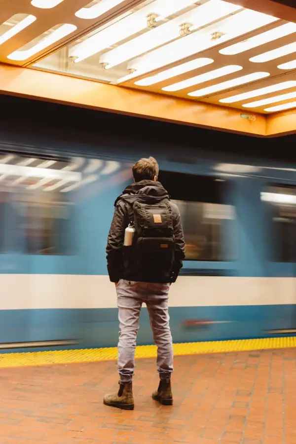 Ein U-Bahn-Zug fährt unscharf in eine Station ein, eine wartende Person steht am Bahnsteigrand